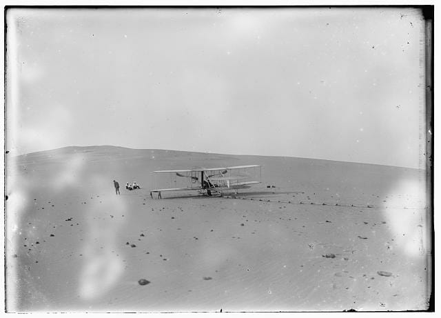 The remodeled 1905 Wright machine, altered to allow the operator to assume a sitting position and to provide a seat for a passenger, on the launching track at Kill Devil Hills. This is apparently the only photograph of this machine taken by the Wright brothers in 1908. Photograph obtained from the Library of Congress Prints and Photographs Division, Washington, D.C.